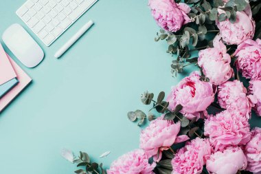 Kadınsı çalışma alanı. Beyaz bilgisayar klavyesi, fare, şakayık çiçekleri, mavi arka planda okaliptüs çiçekleri. Üst Manzara. Uzayı kopyala Düz yatıyordu. Blogger, iş konsepti. Model yap. Doğum günü, Kadın Günü