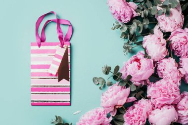 Pembe şakayıklar, okaliptüs çiçekleri, mavi arka planda hediyeler. Uzayı kopyala Düz yerde, üst tarafta. Çiçek kompozisyonu. Düğün, doğum günü, yıldönümü buketi. Kadın günü, Anneler günü.