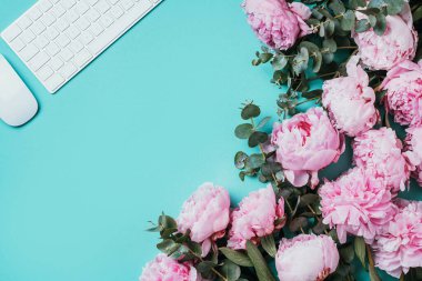 Beyaz bilgisayar klavyesi, fare, şakayık çiçekleri, mavi arka planda okaliptüs çiçekleri. Üst Manzara. Uzayı kopyala Düz yatıyordu. Kadınsı çalışma alanı. Blogger, iş konsepti. Model yap. Doğum günü, Kadın Günü