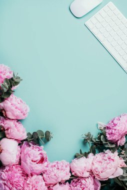 Kadınsı çalışma alanı. Beyaz bilgisayar klavyesi, fare, şakayık çiçekleri, mavi arka planda okaliptüs çiçekleri. Üst Manzara. Uzayı kopyala Düz yatıyordu. Blogger, iş konsepti. Model yap. Doğum günü, Kadın Günü