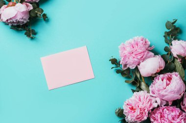 Not defteri, pembe şakayık, mavi arka planda okaliptüs çiçeği olan kadınsı çalışma alanı. Üst görünüm, boşluğu kopyala. Blogcu, kadınsı iş konsepti. Düz yatıyordu. Doğum günü, Kadın Günü. Model.