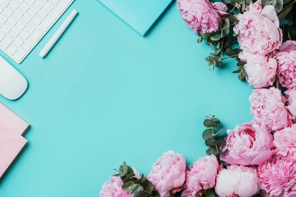 Beyaz klavye, defter ve şakayık, okaliptüs çiçeği, mavi arka planda kopya alanı olan ofis çalışma alanı. Kadınsı çalışma alanı. Düz yatıyordu. Blogger, iş konsepti. Model yap. Doğum günü, Kadın Günü