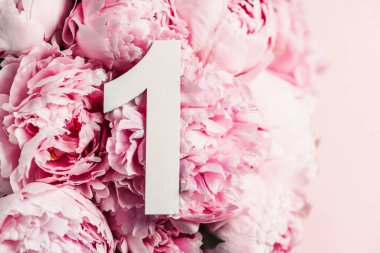 Yaratıcı düzen. Pembe şakayık çiçekleri ve bir numara. Doğum günü tebrik kartı. Yıldönümü konsepti. Üst Manzara. Uzayı kopyala Çiçek arkaplanının üzerinde zarif beyaz bir rakam. Sayısal rakam.