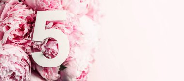 Yaratıcı düzen. Pembe şakayık çiçekleri ve beş beş numara. Doğum günü tebrik kartı. Yıldönümü konsepti. Üst Manzara. Uzayı kopyala Çiçek arkaplanının üzerinde zarif beyaz bir rakam. Sayısal rakam