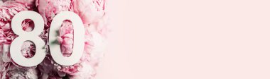 Şakayık çiçekleri, seksen numara. 80 yazılı doğum günü tebrik kartı var. Yıldönümü konsepti. Üst Manzara. Çiçek arka planında beyaz numara. Sayısal rakam, kutlama olayı, şablon, broşür.