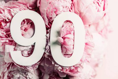 Şakayık çiçekleri, doksan numara. Doğum günü tebrik kartı ve 90 numaralı yazı. Yıldönümü konsepti. Üst Manzara. Çiçek arka planında beyaz numara. Sayısal rakam, kutlama olayı, şablon, broşür.