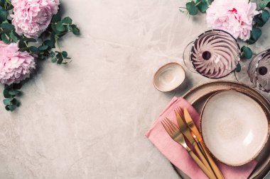Sofra takımı, şenlik masasına servis edilen çiçekler, akşam yemeği. Taş kaplama tabaklar, altın çatal bıçak takımı, okaliptüs dalları, mermer arka planda şakayık çiçekleri. Uzayı kopyala Düz yerde, üst tarafta. Tablo ayarı.
