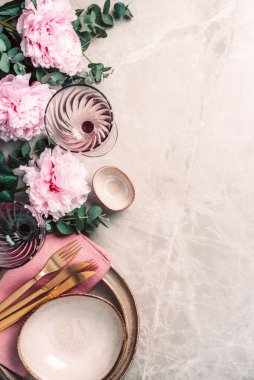 Şakayık, okaliptüs çiçekleri, boş tabaklar, peçete, altın çatal bıçak, şenlik masa servisi için şarap kadehleri mermer zemin üzerinde akşam yemeği. Uzayı kopyala Üst Manzara. Tablo ayarı.