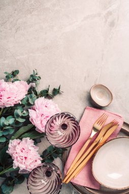 Sofra takımı, şenlik masasına servis edilen çiçekler, akşam yemeği. Taş kaplama tabaklar, altın çatal bıçak takımı, okaliptüs dalları, mermer arka planda şakayık çiçekleri. Uzayı kopyala Düz yerde, üst tarafta. Tablo ayarı.