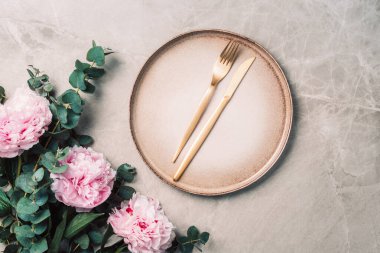 Şakayık, okaliptüs çiçekleri, boş tabaklar, peçete, altın çatal bıçak, şenlik masa servisi için şarap kadehleri mermer zemin üzerinde akşam yemeği. Uzayı kopyala Üst Manzara. Tablo ayarı.