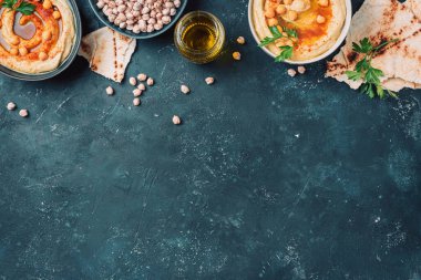 Nohut humusu, zeytinyağı, çiğ nohut, tütsülenmiş paprika, koyu arkaplanda pide. Ortadoğu, Yahudi mutfağı ya da Arap yemekleri. Üst Manzara. Uzayı kopyala Atıştırmalıklar hazır. Vejetaryen, vejetaryen gıda konsepti.