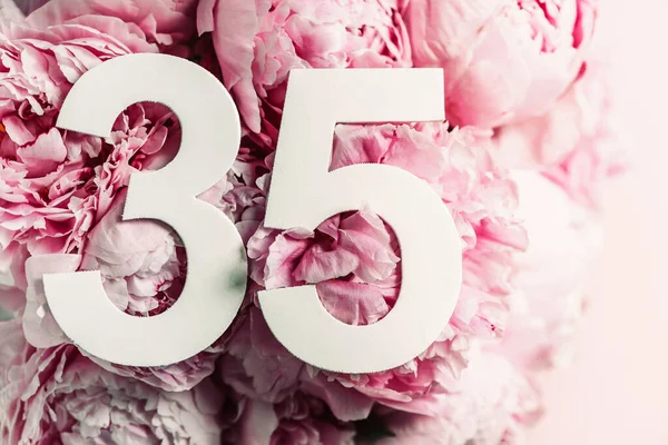 Şakayık çiçekleri, 35 numara. Doğum günü tebrik kartında 35 yazılıydı. Yıldönümü konsepti. Üst Manzara. Çiçek arka planında beyaz numara. Sayısal rakam, kutlama olayı, şablon, broşür.