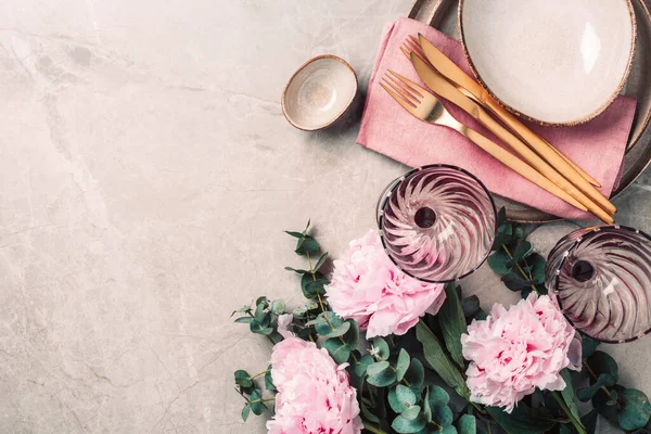 Şakayık, okaliptüs çiçekleri, boş tabaklar, peçete, altın çatal bıçak, şenlik masa servisi için şarap kadehleri mermer zemin üzerinde akşam yemeği. Uzayı kopyala Üst Manzara. Tablo ayarı.