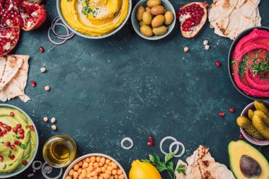 Sarı zerdeçal humusu, yeşil maydanoz humusu ve koyu arkaplanda kırmızı pancar humusu, limon, susam, zeytinyağı, pide, avokado, nar. Orta Doğu, Yahudi, Arap mutfağı