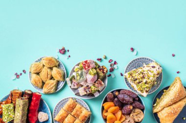 Mavi arka planda Orta Doğu tatlıları. Arap tatlısı, baklava, halva, rahat lokum, şerbet, fındık, şam fıstığı, hurma, kuru üzüm, kayısı, kilise kilisesi, kurabiye. Üst Manzara. Düz yatıyordu. Boşluğu kopyala.