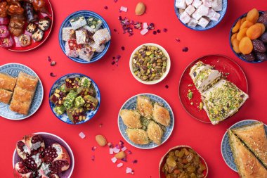 Kırmızı arka planda geleneksel Türk zevki. Üst Manzara. Düz yatıyordu. Uzayı kopyala Arap tatlısı, baklava, halva, rahat lokum, şerbet, fındık, fıstık, hurma, kuru üzüm, kayısı, kilise kilisesi.