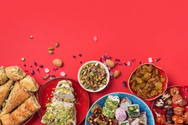 Kırmızı arka planda geleneksel Türk zevki. Üst Manzara. Düz yatıyordu. Uzayı kopyala Arap tatlısı, baklava, halva, rahat lokum, şerbet, fındık, fıstık, hurma, kuru üzüm, kayısı, kilise kilisesi.