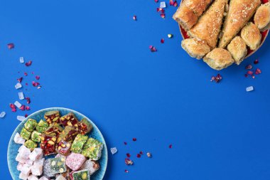 Mavi arka planda Orta Doğu tatlıları. Arap tatlısı, baklava, halva, rahat lokum, şerbet, fındık, şam fıstığı, hurma, kuru üzüm, kayısı, kilise kilisesi, kurabiye. Üst Manzara. Düz yatıyordu. Boşluğu kopyala.