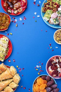 Mavi arka planda Orta Doğu tatlıları. Arap tatlısı, baklava, halva, rahat lokum, şerbet, fındık, şam fıstığı, hurma, kuru üzüm, kayısı, kilise kilisesi, kurabiye. Üst Manzara. Düz yatıyordu. Boşluğu kopyala.