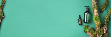 Yeşil cam şampuan, sabun, yeşil arka planda saç kremi ve ağaç kabuğunun üstünde doğal yosun. Üst görünüm, boşluğu kopyala. Model için boş etiket. Cilt bakımı, organik vücut tedavisi, spa konsepti.