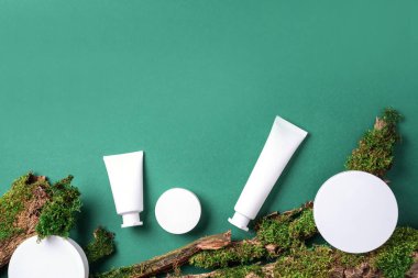 Krema kavanozu, nemlendirici losyon, şampuan ya da diğer kozmetik ürünler yeşil arka planda beyaz boş şişede yosun ve ağaç kabuğu ile birlikte. Cilt bakımı, organik vücut bakımı, spa konsepti. Vejetaryen çevre dostu.