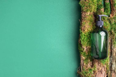 Yeşil cam şampuan, sabun, yeşil arka planda saç kremi ve ağaç kabuğunun üstünde doğal yosun. Üst görünüm, boşluğu kopyala. Model için boş etiket. Cilt bakımı, organik vücut tedavisi, spa konsepti.