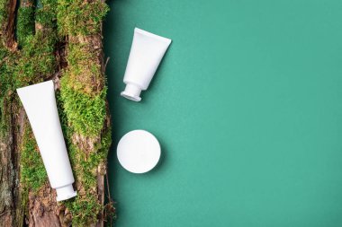 Krema kavanozu, nemlendirici losyon, şampuan ya da diğer kozmetik ürünler yeşil arka planda beyaz boş şişede yosun ve ağaç kabuğu ile birlikte. Cilt bakımı, organik vücut bakımı, spa konsepti. Vejetaryen çevre dostu.