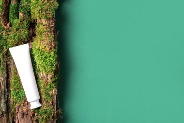 Yeşil arka planda beyaz etiketsiz kozmetik şişesi dalların üzerinde doğal yosun, ağaç kabuğu. Cilt bakımı, organik vücut bakımı, spa konsepti. Vegan çevre dostu kozmetoloji ürünü. Organik Kozmetik