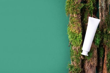 Krema kavanozu, nemlendirici losyon, şampuan ya da diğer kozmetik ürünler kahverengi arka planda beyaz boş şişede, yosun ve ağaç kabuğuyla. Cilt bakımı, organik vücut bakımı, spa konsepti. Vejetaryen çevre dostu.