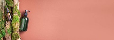 Yeşil cam şampuan, sabun, kahverengi arka planda saç kremi ve ağaç kabuğunun üstünde doğal yosun. Üst görünüm, boşluğu kopyala. Model için boş etiket. Cilt bakımı, organik vücut tedavisi, spa konsepti.