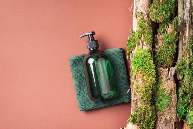 Kahverengi arka planda etiketsiz kozmetik şişesi dalların üzerinde doğal yosun, ağaç kabuğu. Cilt bakımı, organik vücut bakımı, spa konsepti. Vegan çevre dostu kozmetoloji ürünü. Organik Kozmetik