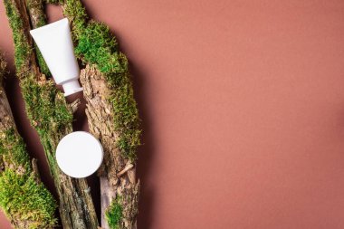 Kahverengi arka planda beyaz etiketsiz kozmetik şişesi dalların üzerinde doğal yosun, ağaç kabuğu. Cilt bakımı, organik vücut bakımı, spa konsepti. Vegan çevre dostu kozmetoloji ürünü. Organik Kozmetik