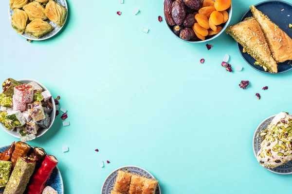 Mavi arka planda Orta Doğu tatlıları. Arap tatlısı, baklava, halva, rahat lokum, şerbet, fındık, şam fıstığı, hurma, kuru üzüm, kayısı, kilise kilisesi, kurabiye. Üst Manzara. Düz yatıyordu. Boşluğu kopyala.