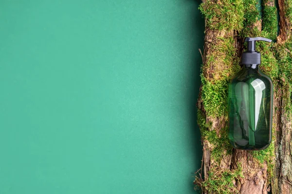 Yeşil cam şampuan, sabun, yeşil arka planda saç kremi ve ağaç kabuğunun üstünde doğal yosun. Üst görünüm, boşluğu kopyala. Model için boş etiket. Cilt bakımı, organik vücut tedavisi, spa konsepti.