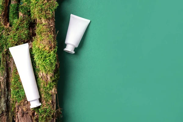 Krema kavanozu, nemlendirici losyon, şampuan ya da diğer kozmetik ürünler kahverengi arka planda beyaz boş şişede, yosun ve ağaç kabuğuyla. Cilt bakımı, organik vücut bakımı, spa konsepti. Vejetaryen çevre dostu.