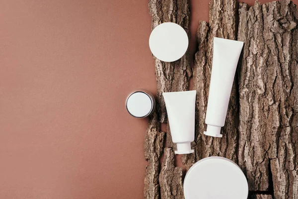 Kuru ahşap kabuk arka planında etiketsiz beyaz kozmetik şişe. Cilt bakımı, organik vücut tedavisi, deri beslenme konsepti. Çevre dostu ürün. Organik kozmetik ürünleri. Nemlendirici, kuru cilt konsepti.