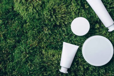 Krema kavanozu, nemlendirici losyon, şampuan ya da yeşil yosun arka planında beyaz boş şişe içindeki diğer kozmetik ürünler. Cilt bakımı, organik vücut bakımı, spa konsepti. Vejetaryen çevre dostu. Biyofilik tasarım.