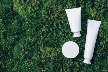 Krema kavanozu, nemlendirici losyon, şampuan ya da yeşil yosun arka planında beyaz boş şişe içindeki diğer kozmetik ürünler. Cilt bakımı, organik vücut bakımı, spa konsepti. Vejetaryen çevre dostu. Biyofilik tasarım.