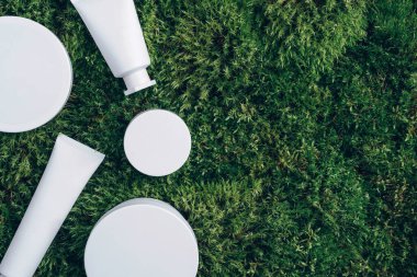 Krema kavanozu, nemlendirici losyon, şampuan ya da yeşil yosun arka planında beyaz boş şişe içindeki diğer kozmetik ürünler. Cilt bakımı, organik vücut bakımı, spa konsepti. Vejetaryen çevre dostu. Biyofilik tasarım.