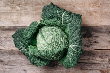 Çiğ yeşil lahana dokusu. Ahşap arka planda organik savoy lahanası. Üst Manzara. Uzayı kopyala Vejetaryen ve vejetaryen diyet kavramı.