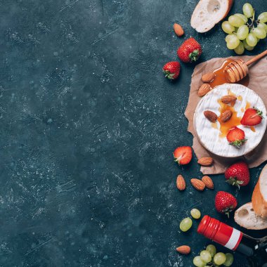 Üzümlü camembert peyniri, badem fıstığı, baget, çilek, bal, kırsal kesimde şarap. Üst Manzara. Uzayı kopyala Romantik randevu gecesi için gurme aperatifi. Sevgililer Günü, aşk konsepti.