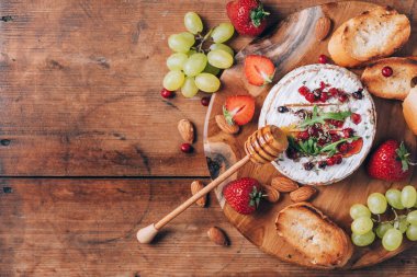 Ballı kamembert peyniri, roka, kızılcık, kızarmış ekmek, üzüm, çilek, ahşap tahtada badem fıstığı. Üst Manzara. Uzayı kopyala Romantik randevu gecesi. Sevgililer Günü, aşk konsepti.