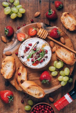 Romantik randevu gecesi. Sevgililer Günü, aşk konsepti. Ballı kamembert peyniri, roka, kızılcık, şarap, kızarmış ekmek, üzüm, çilek, ahşap tahtada badem fıstığı. Üst Manzara. Boşluğu kopyala.