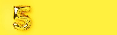Yaratıcı düzen. Altın folyo balon numarası ve rakam 5-5. Doğum günü tebrik kartı. Yıldönümü konsepti. Üst Manzara. Uzayı kopyala Sarı arkaplan üzerinde zarif altın rakam. Sayısal rakam