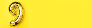 Yaratıcı düzen. Altın folyo balon numarası ve 99. rakam. Doğum günü tebrik kartı. Yıldönümü konsepti. Üst Manzara. Uzayı kopyala Sarı arkaplan üzerinde zarif altın rakam. Sayısal rakam