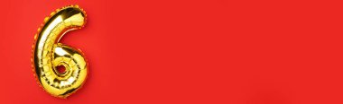 Yaratıcı düzen. Altın folyo balon numarası ve altı haneli sayı. Doğum günü tebrik kartı. Yıldönümü konsepti. Üst Manzara. Uzayı kopyala Kırmızı zemin üzerinde zarif altın rakam. Sayısal rakam