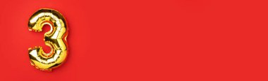 Yaratıcı düzen. Altın folyo balon numarası ve 3 haneli rakam. Doğum günü tebrik kartı. Yıldönümü konsepti. Üst Manzara. Uzayı kopyala Kırmızı zemin üzerinde zarif altın rakam. Sayısal rakam
