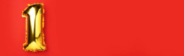 Yaratıcı düzen. Altın folyo balon numarası ve sayı 1 1. Doğum günü tebrik kartı. Yıldönümü konsepti. Üst Manzara. Uzayı kopyala Kırmızı zemin üzerinde zarif altın rakam. Sayısal rakam.