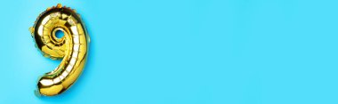 Yaratıcı düzen. Altın folyo balon numarası ve 99. rakam. Doğum günü tebrik kartı. Yıldönümü konsepti. Üst Manzara. Uzayı kopyala Mavi arka planda zarif altın rakamı. Sayısal rakam