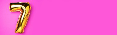 Yaratıcı düzen. Altın folyo balon numarası ve 7 haneli rakam. Doğum günü tebrik kartı. Yıldönümü konsepti. Üst Manzara. Uzayı kopyala Pembe arka planda zarif altın rakamı. Sayısal rakam